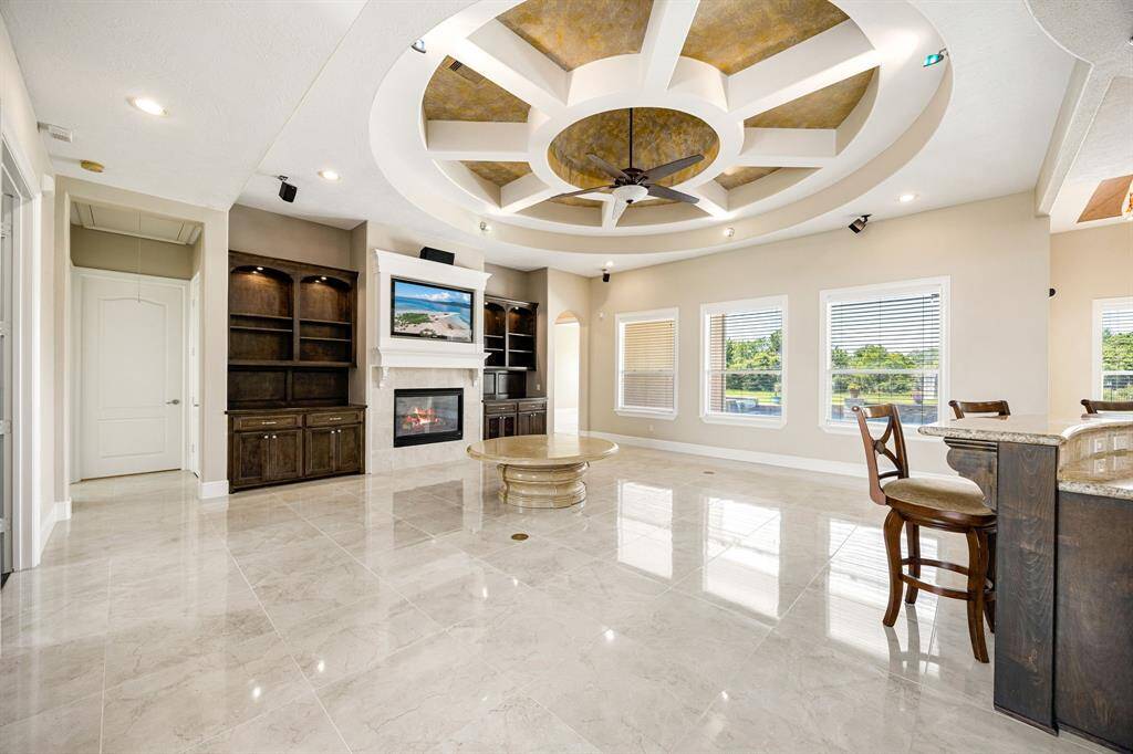 Living room is open to the kitchen and has custom, accented ceiling and built-in shelving which marries into the kitchen cabinetry.
