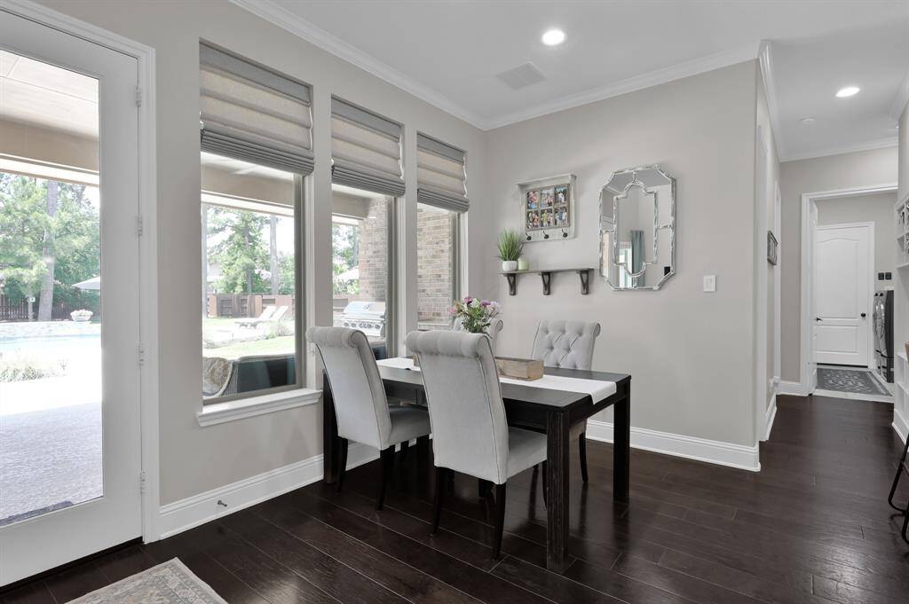 This Breakfast room area features elegant warm wood flooring and neutral walls, accentuated by large windows offering a view of the backyard pool. The space sits right off the Kitchen and provides additional entertaining space or intimate dining.