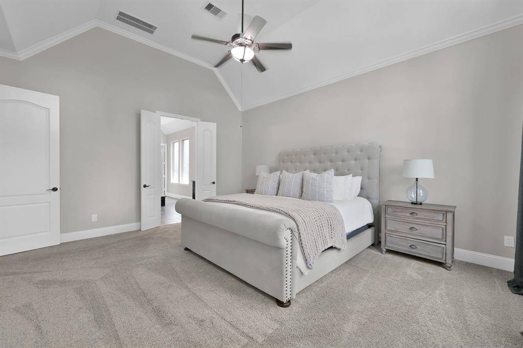 This spacious Owner's Retreat Bedroom features a high ceiling, soft neutral walls, and plush carpet. Double doors lead to an adjoining en-suite Owner's Retreat Bathroom space, enhancing the room's openness and flow.