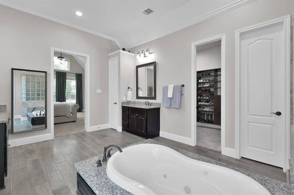 This photo showcases the front entrance of a modern, yet traditional home featuring a stone facade, elegant double doors, and well-maintained landscaping with shrubs and flowers, creating an inviting and charming curb appeal.
