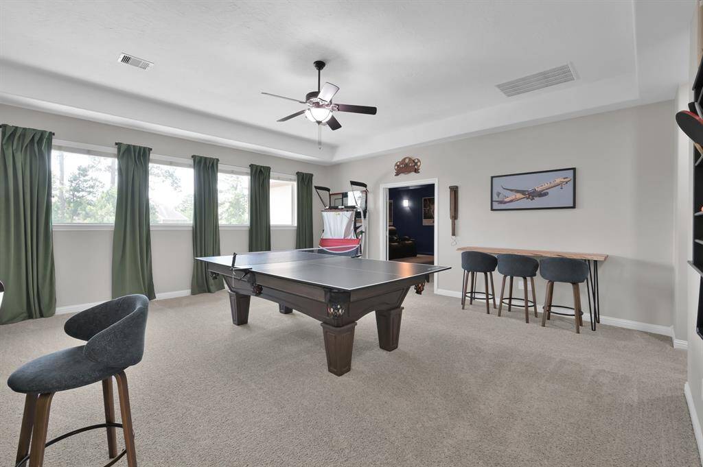 This spacious game room features a ceiling fan, abundant natural light from multiple windows. There's plenty of space to accommodate a bar area and a standard sized pool table and/or ping pong table,  perfect for entertainment and relaxation.