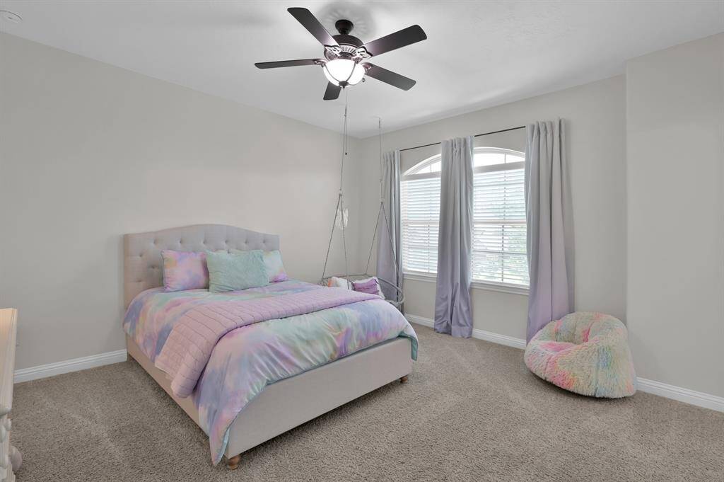 This bedroom features a cozy, carpeted space with soft gray walls. It includes a ceiling fan, and a large windows, providing ample natural light.  Another over-sized secondary room which shares a Jack and Jill bathroom setup with the third bedroom on this level.