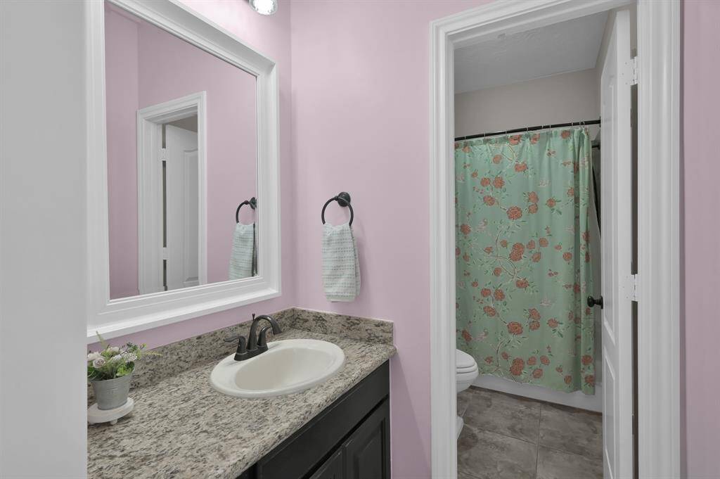 This bathroom features a granite countertop with a white sink, tile flooring and a large mirror. This is the second vanity area of the shared Jack and Jill Bathroom.
