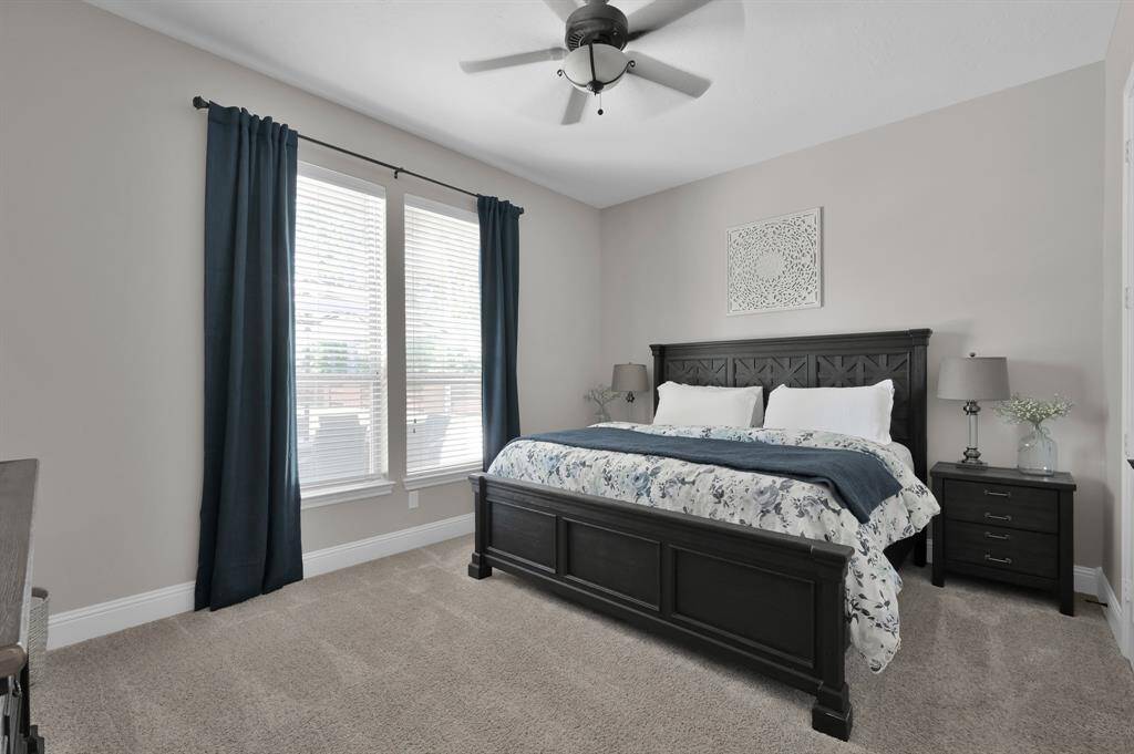 This is the second Primary Bedroom located on the main level.  It is bright and inviting with neutral walls, plush carpet, and natural light from large windows.  It can easily be a used as a Guest Suite or another family bedroom.  There is a spacious en-suite Bathroom which boasts a large walk-in shower and ample counter top with plenty of storage.