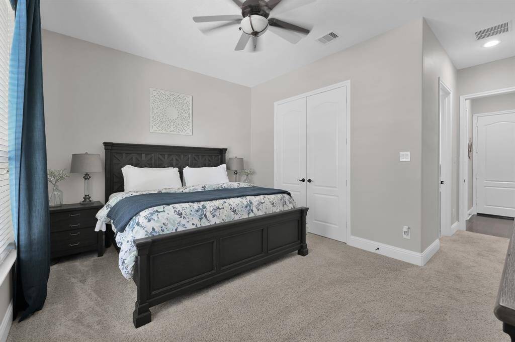 This second Primary bedroom features neutral walls, soft carpeted flooring, a ceiling fan, great natural light and an en-suite private bathroom.  A spacious closet is accessible from double closet doors. The room is located on the opposite side of the home from the Owner's Retreat providing a more private and quiet area to rest.