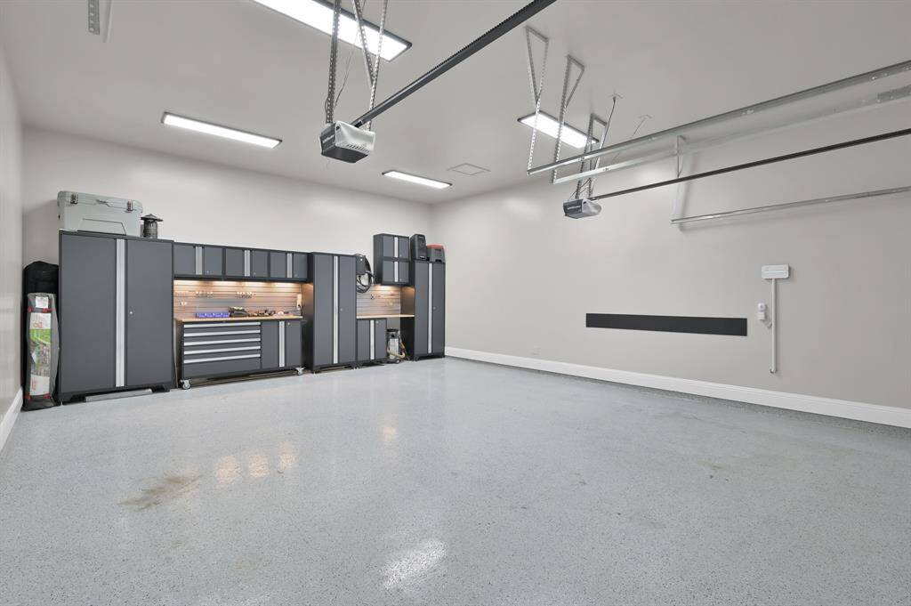 This spacious, well-lit 2-car garage features a clean epoxy floor, ample overhead lighting, and plenty of storage space as illustrated by the current storage system.  This garage also boasts an EV car charger.