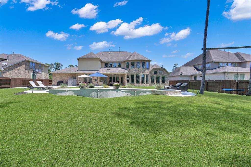 Spacious backyard with a well-maintained lawn, a central pool, and a seating area. The home features large windows, offering plenty of natural light. Ideal for outdoor entertaining and relaxation.