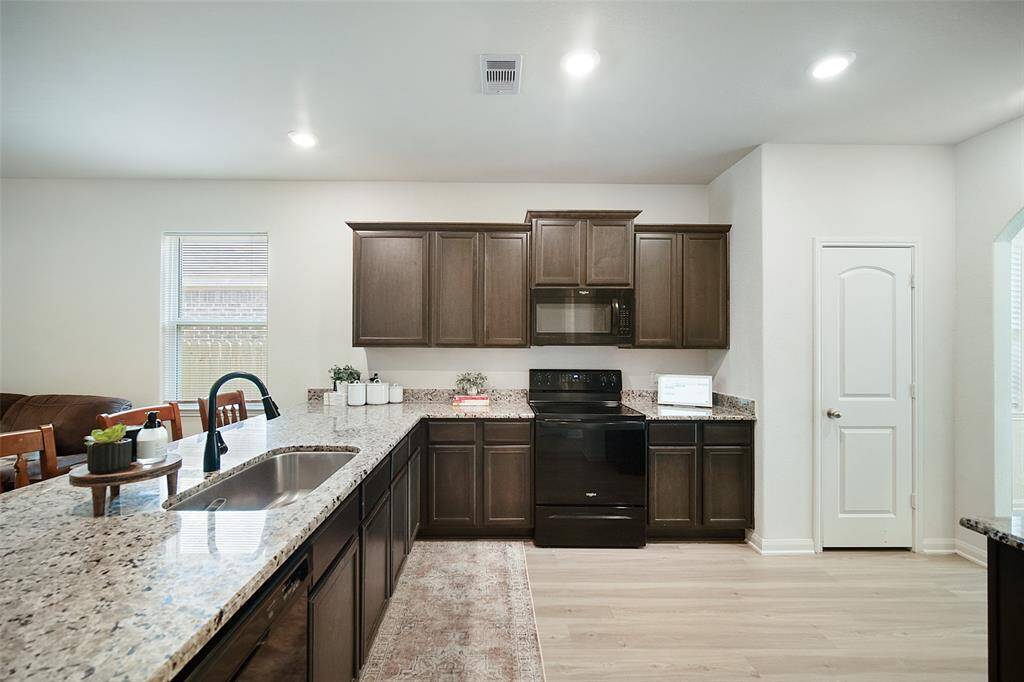 The kitchen offers electric cooking, a deep sink, and convenient space for seating at the island at left.  The dedicated pantry is at right.