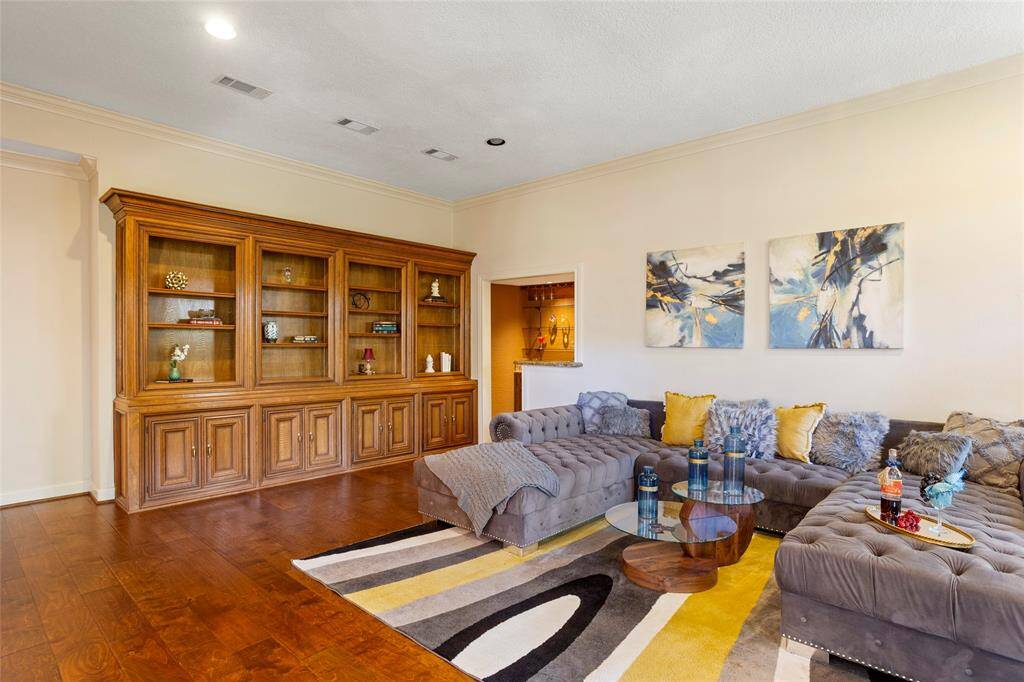 Wet bar has wood cabinets and glass shelving. Bar refrigerator is included!