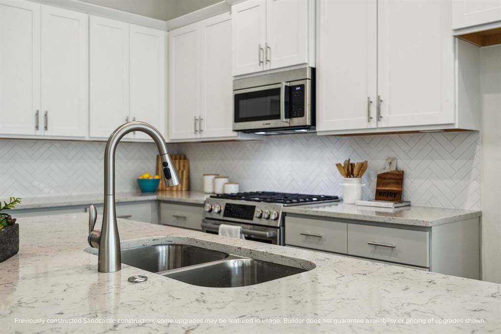 From the stainless steel undermount sink to the Moen pull-down faucet, every detail here feels elevated. Designer-selected backsplashes add just the right touch of texture and personality.
