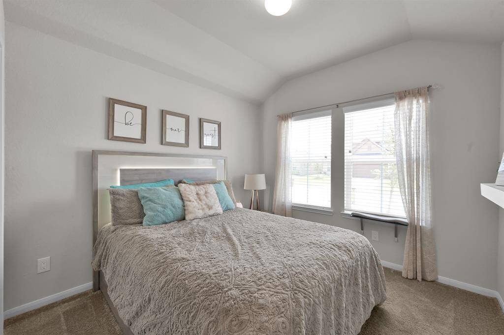 This cozy secondary bedroom features ample natural light and an inviting atmosphere.