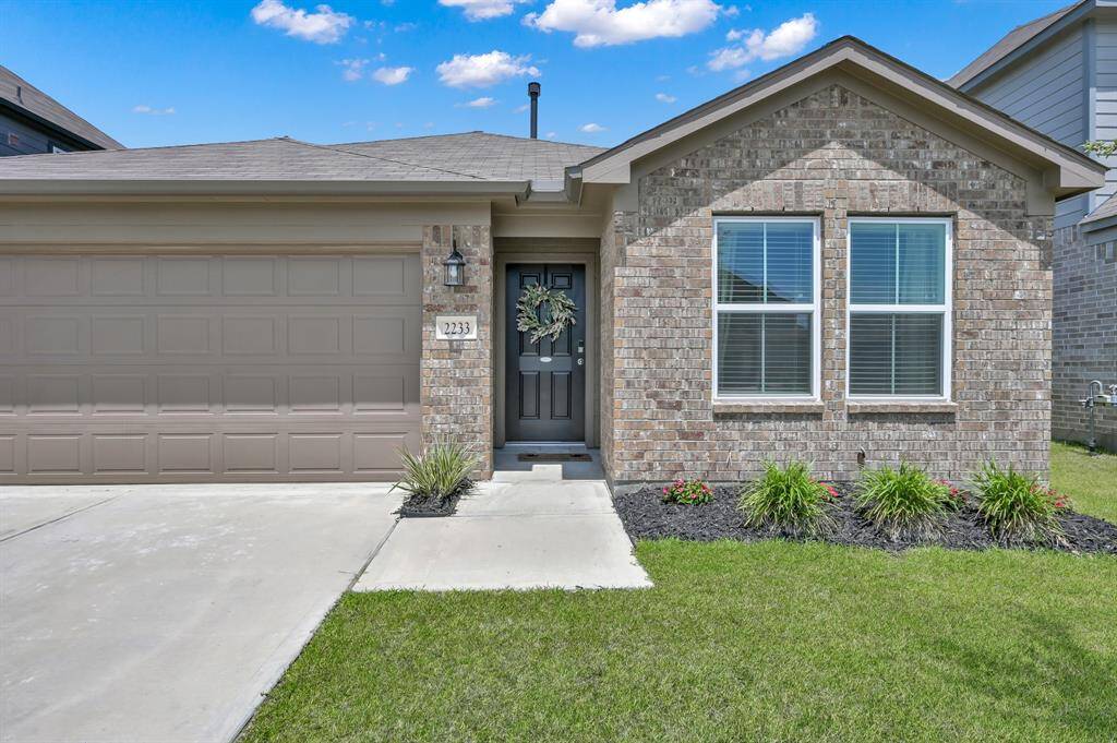 This charming single-story home features a brick exterior with a two-car garage and well-maintained front yard landscaping.