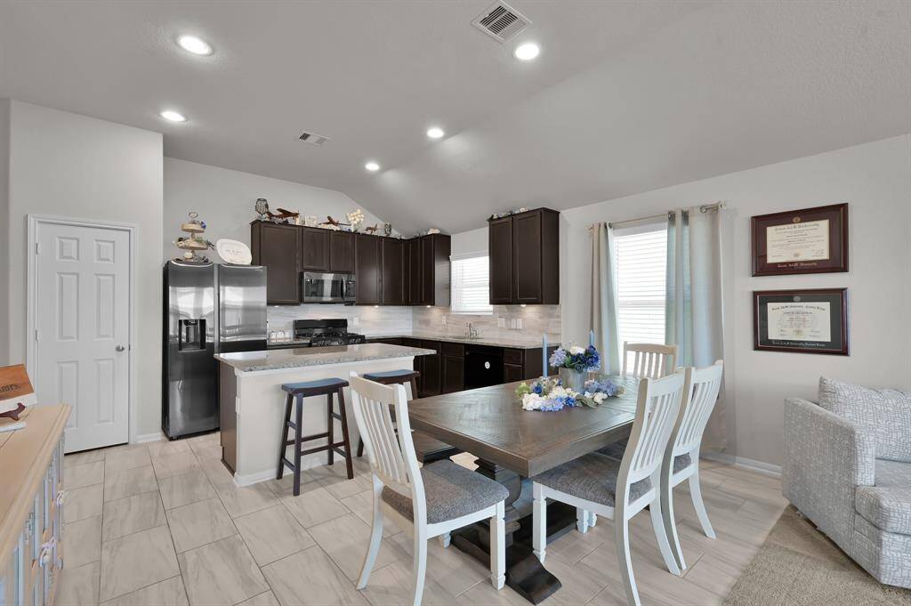This home showcases a modern kitchen and dining area with sleek dark cabinets and stainless steel appliances. The space is well-lit with recessed lighting and offers a neutral color palette.