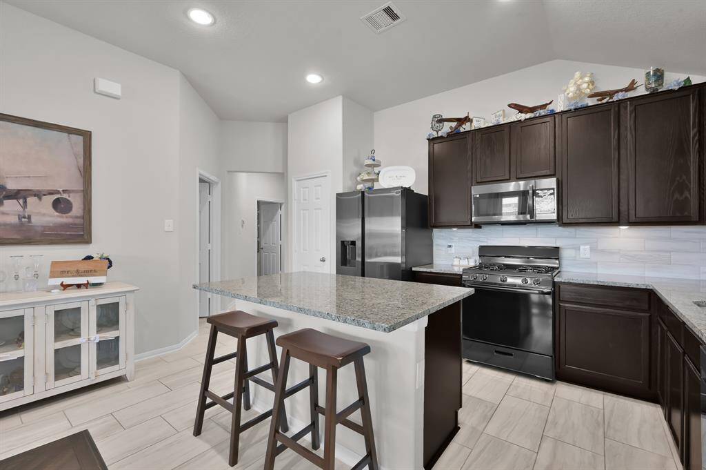The spacious island with bar seating enhances functionality, while the light tile flooring and recessed lighting create a bright, inviting atmosphere.