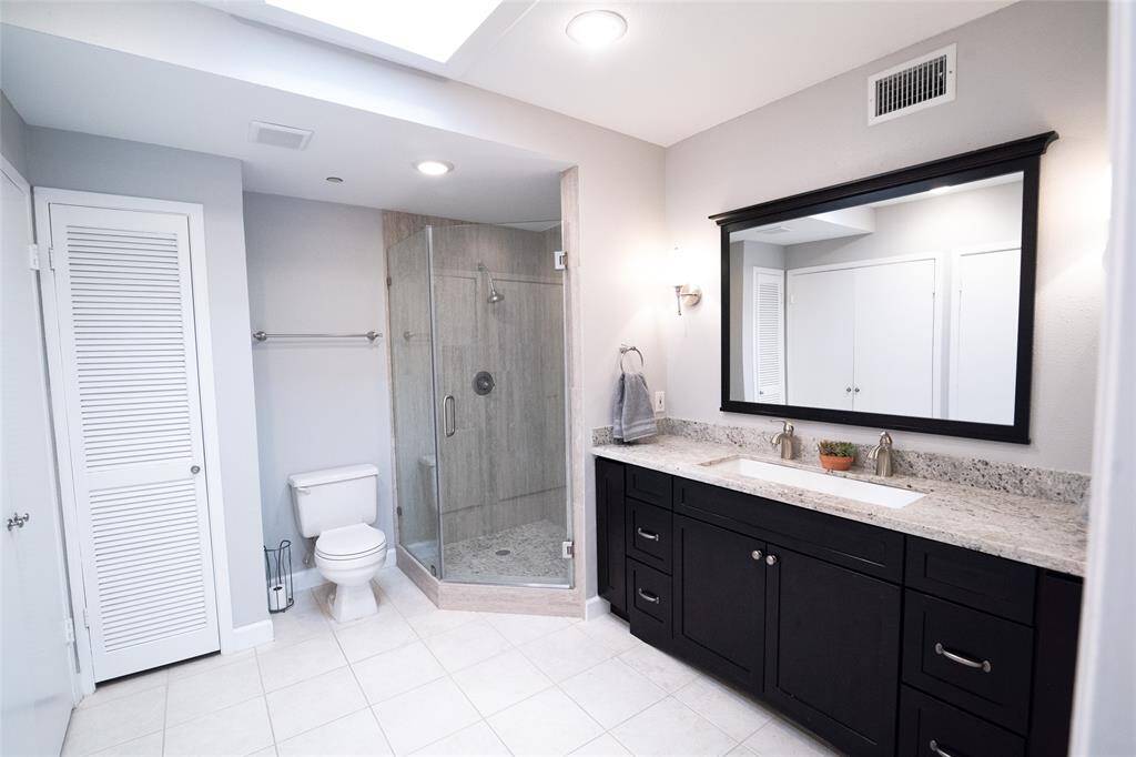 Light-filled primary bathroom featuring a ceiling window for natural illumination, a clean modern design, an ample closet, and a serene, spa-like atmosphere.