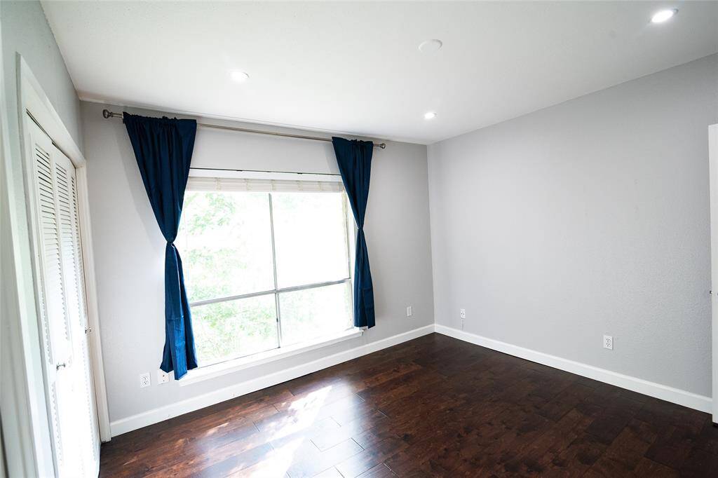 Spacious bedroom featuring large windows with lush green views, and hardwood flooring
