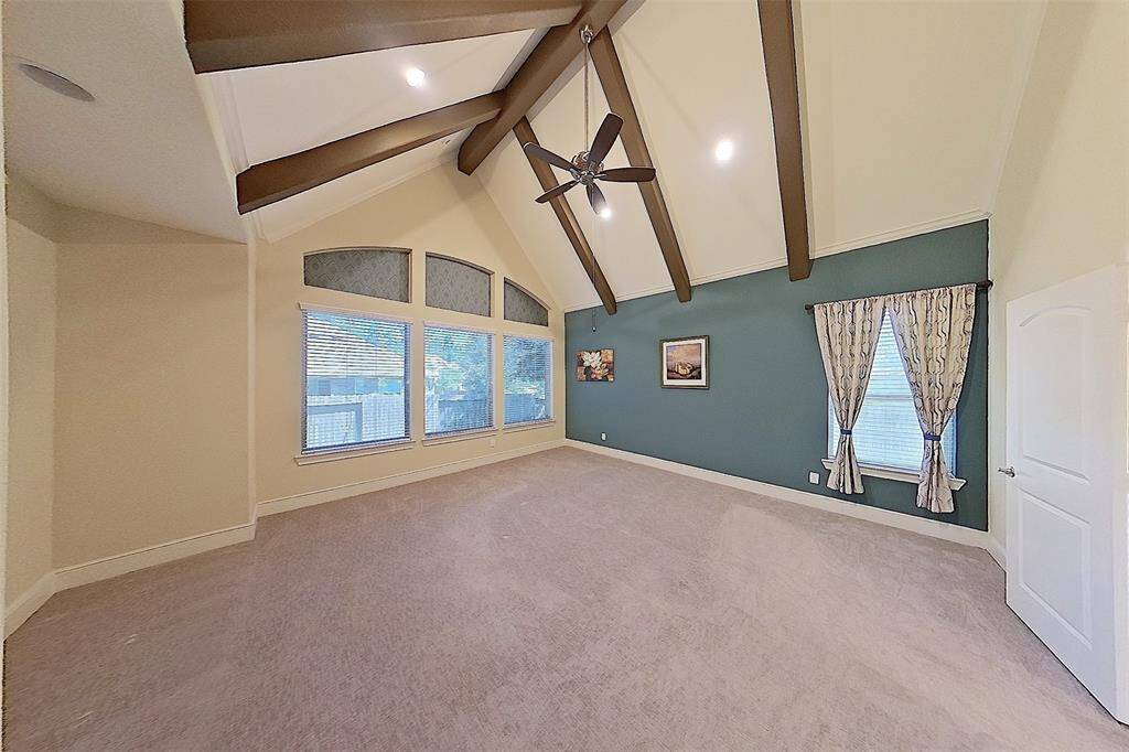 Primary bedroom with soaring ceiling and beautiful accent wall