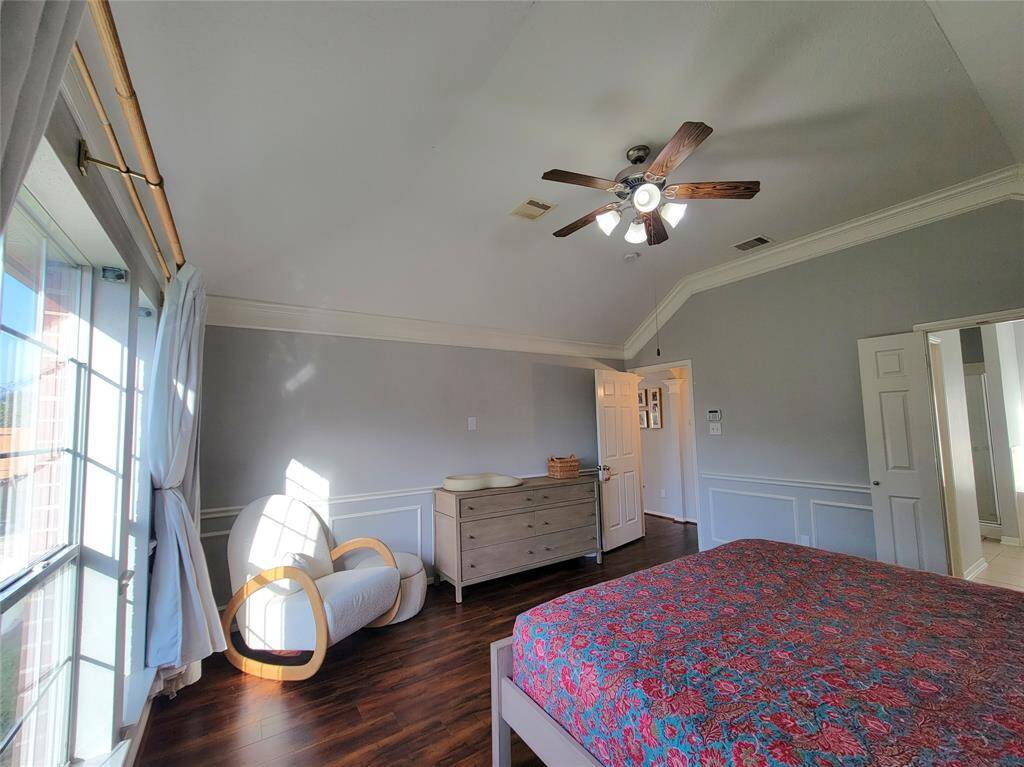Bright and airy bedroom with large windows, hardwood floors, and a ceiling fan. Features a cozy reading nook and neutral decor for a modern feel.