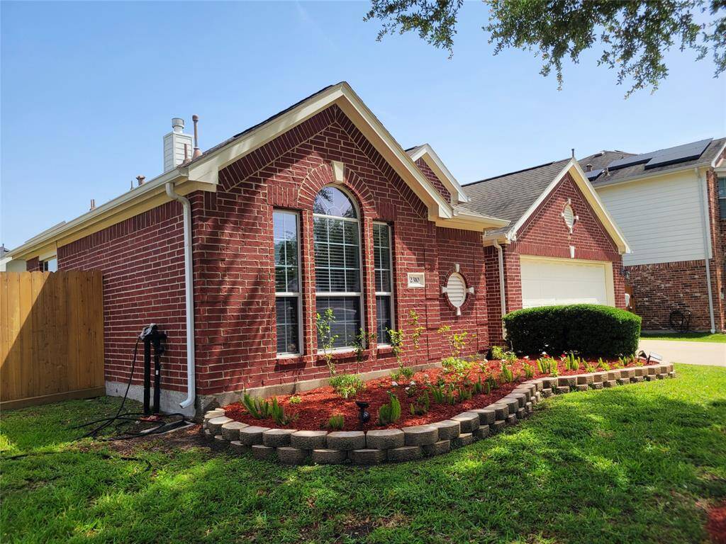 Charming brick home with a well-maintained front yard and attractive landscaping. Features a two-car garage, arched windows, and a cozy entryway. Located on a corner lot with a wooden fence offering privacy.
