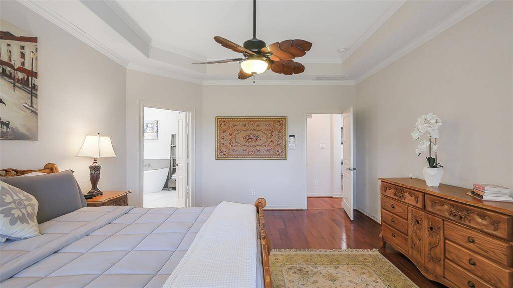 The large primary suite sits in the back of the home for privacy.  Trey ceiling, fan, bay window, plantation shutters, crown molding, wood flooring and fresh paint.