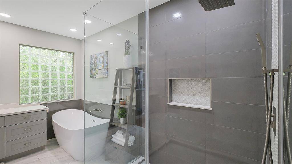 Frameless glass shower door on tiled remodeled walk-in shower.  Soaking tub with tile accent wall.