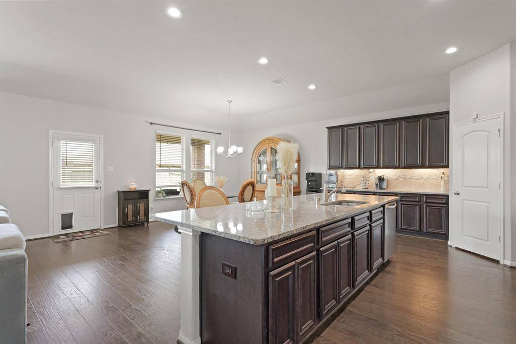 The kitchen features dark cabinetry, granite counters, under-cabinet lighting, and tons of prep space.