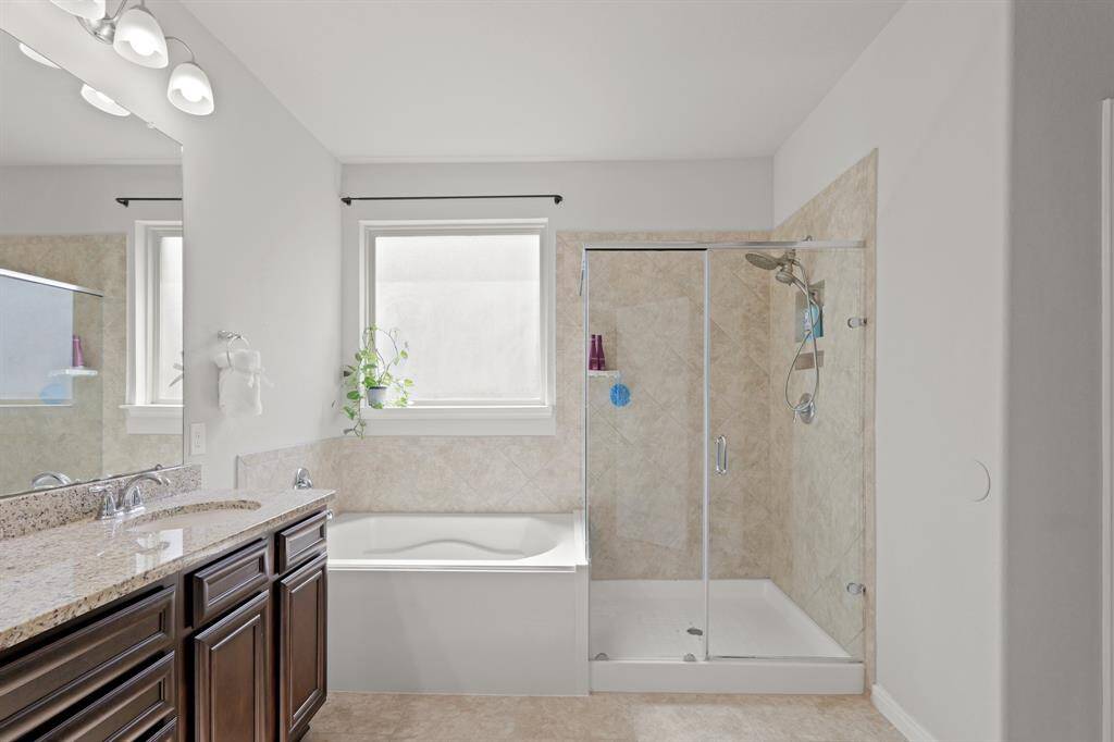 Tile surround, glass enclosure, and natural light elevate this shower-and-tub combo beyond builder-basic.