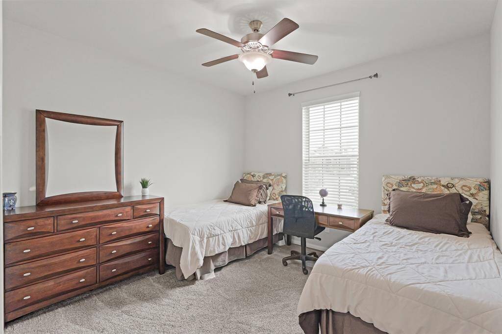 This front-facing secondary bedroom offers flexible space for kids, guests, or roommates—complete with a ceiling fan, generous natural light, and room for two beds plus a study nook.