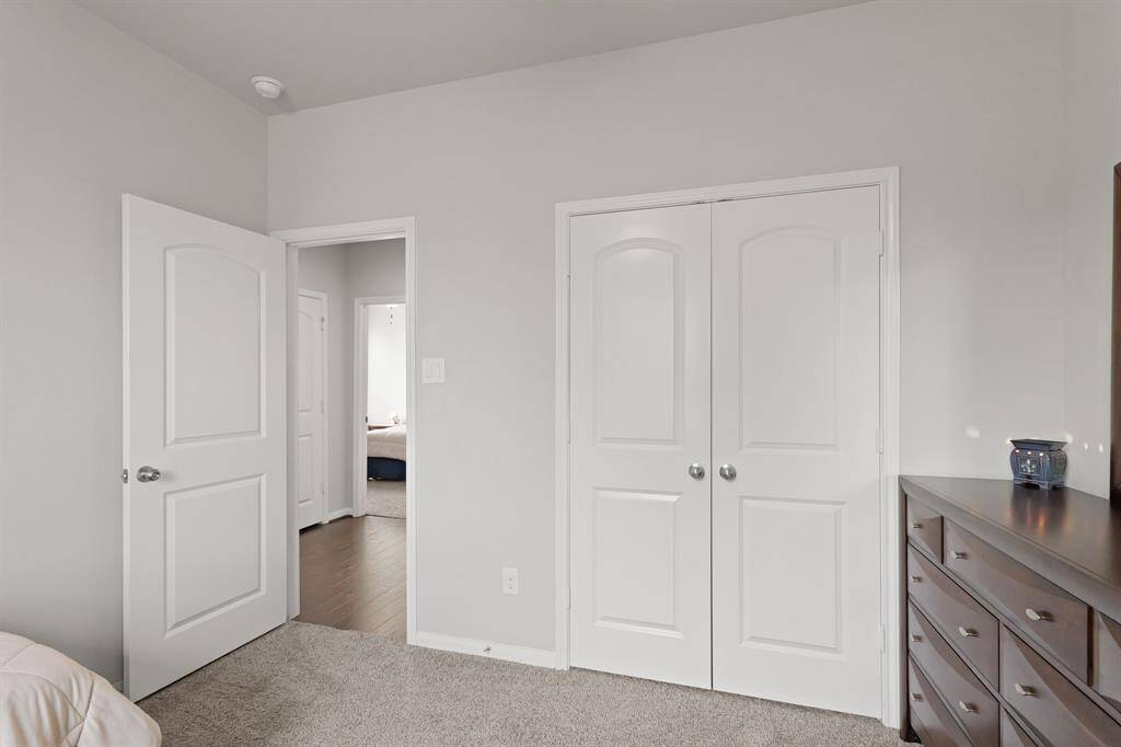 A peek toward the hallway shows this room’s convenient access to the shared bath and other bedrooms, with a spacious closet tucked behind double doors for easy organization.
