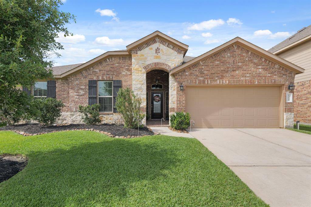 Curb appeal on point—stone and brick exterior with fresh landscaping and lush grass maintained by a full sprinkler system.