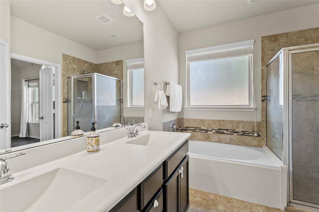 Ease into the evening in a bathroom that feels like it was made just for you. The double vanity gives you room to spread out while getting ready, and the oversized mirror catches the soft natural light streaming through the frosted window. A soaking tub invites long, quiet moments, while the glass-enclosed shower adds a modern, polished edge. Everything is in its place—calm, clean, and yours.