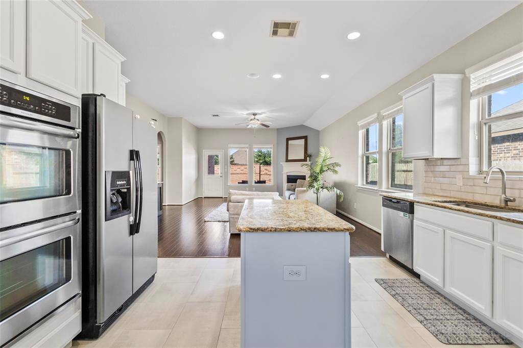 This open-concept layout nails the flow—whether you're cooking, entertaining, or just lounging. The kitchen’s granite island and stainless steel appliances open right into a light-filled living area anchored by a cozy corner fireplace, all framed by views of the backyard. It’s the kind of space that keeps the conversation going.