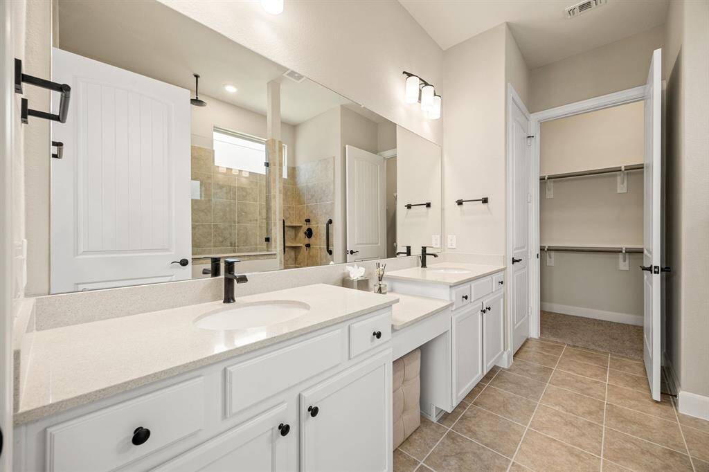 Primary bath with dual sinks and vanity area. Primary bath leads into the large closet.