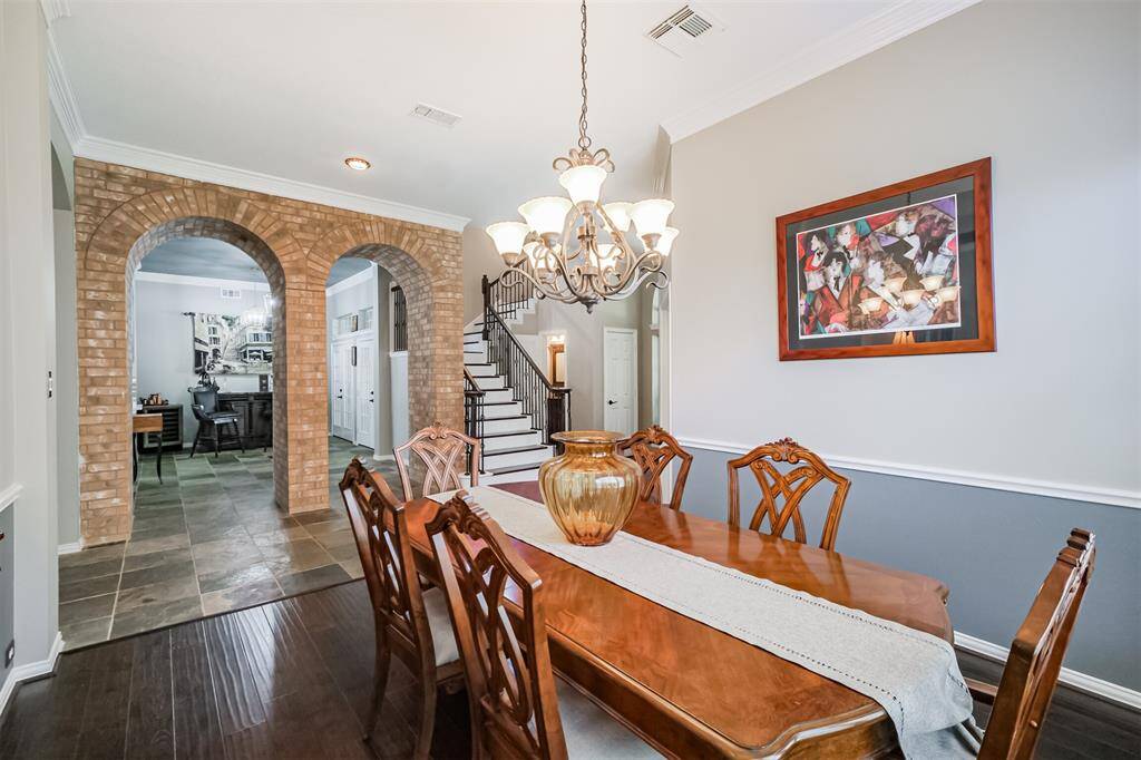 Enjoy the elegant dining room view of the foyer, featuring charming brick archways and a graceful staircase.