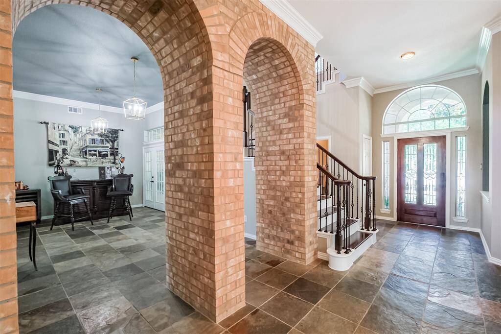Step into the inviting foyer and admire the elegant archways leading to the sunlit front room, perfect for a formal living space or bar area