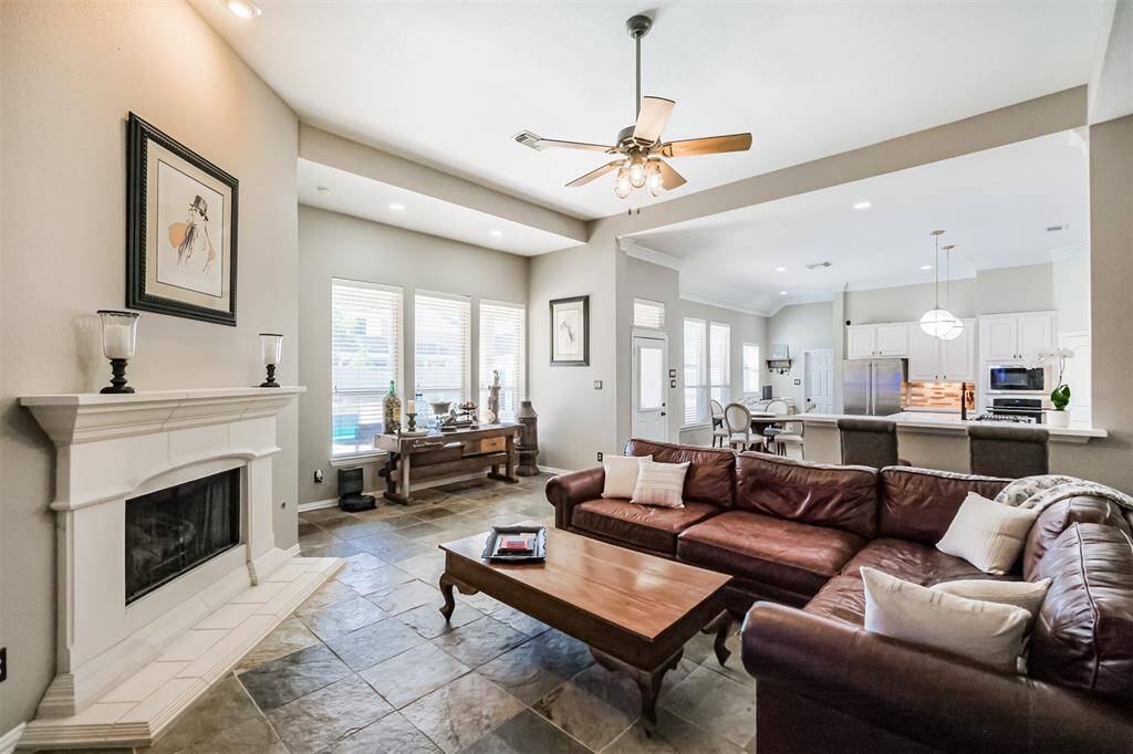 Relax in luxury in the open living room with soaring ceilings, a cozy gas log fireplace, stunning slate floors, and pool views.