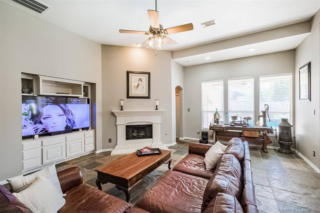 The living are offers cozy elegance with a built-in entertainment center, a stunning gas fireplace with a cast stone surround, and abundant natural light from expansive windows.