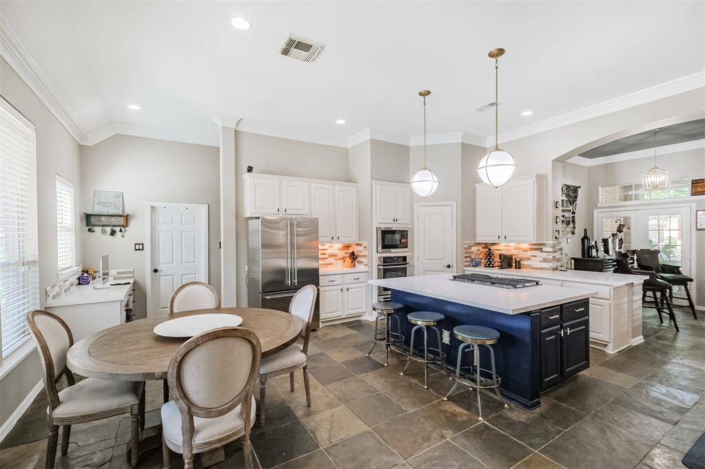 The modern updated kitchen has stainless steel appliances, quartz countertops, stylish painted cabinets, and modern pendant lighting.