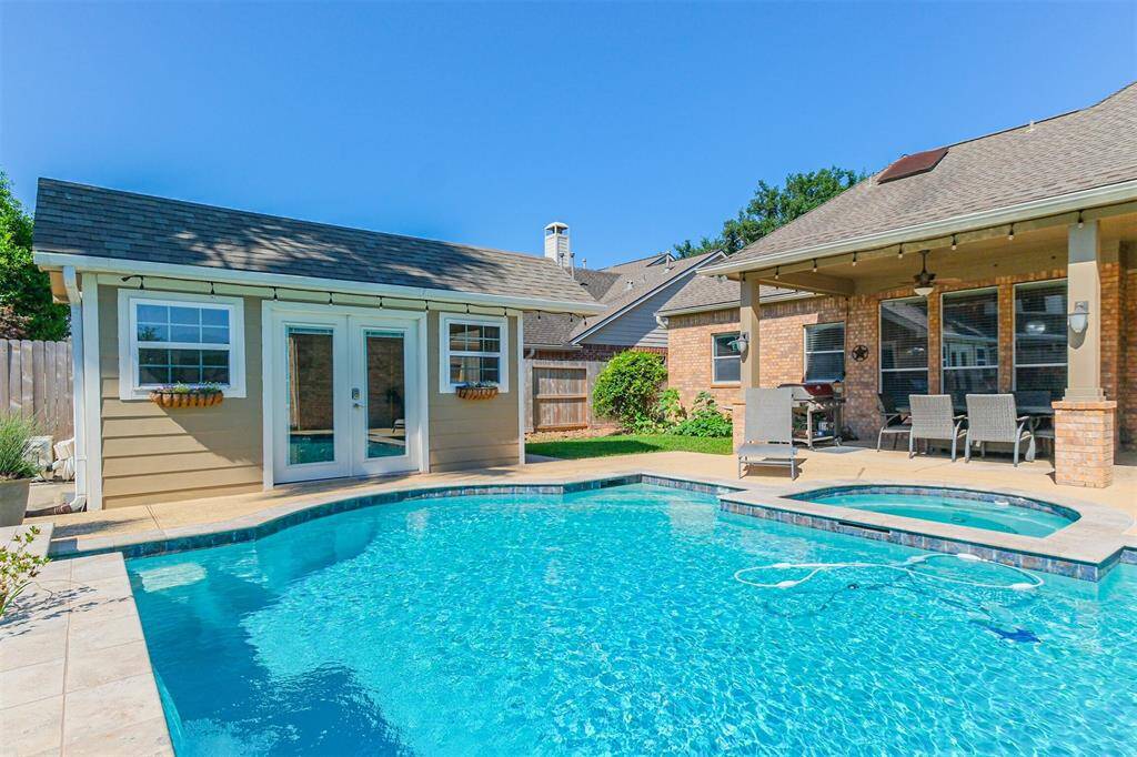Enjoy the perfect backyard retreat with a stunning pool, hot tub, spacious covered patio, and an air-conditioned pool house for ultimate relaxation and entertaining.