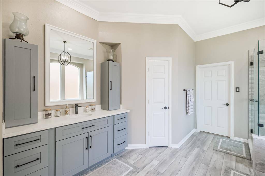 The elegant primary bath features double vanities with quartz countertops, under-mount sinks, and stylish painted corner cabinets for ample storage.