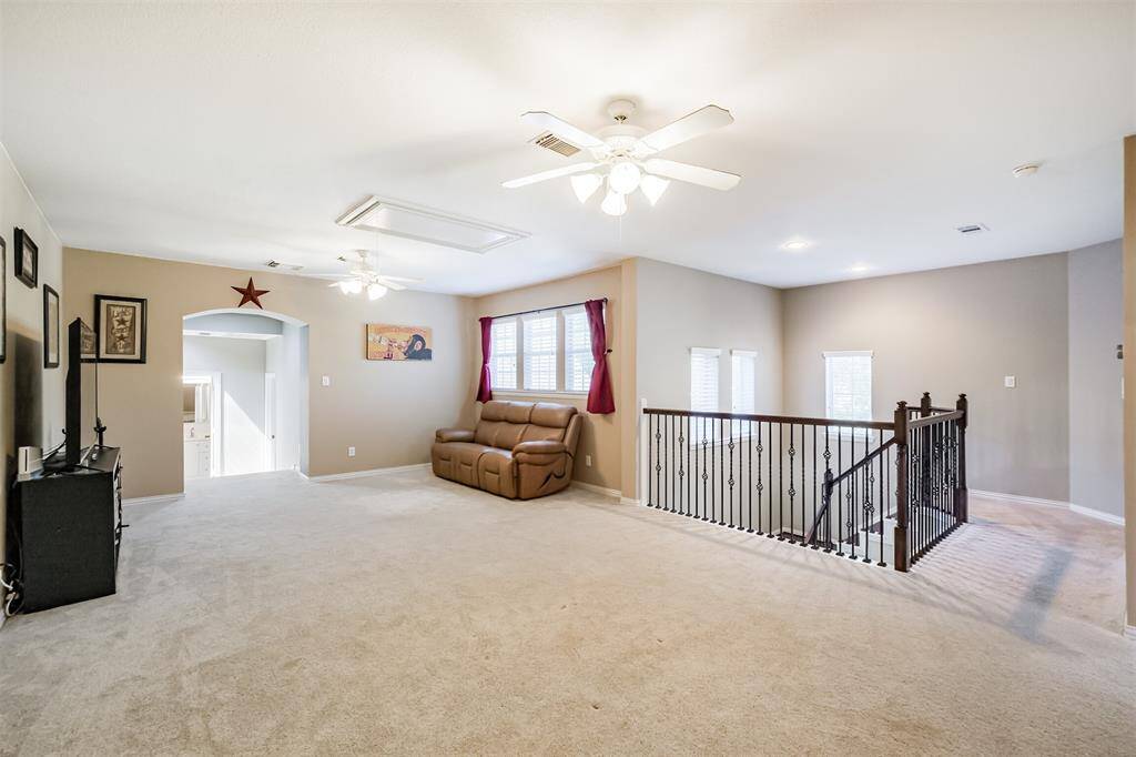 This inviting game room is located at the top of the main stairs, featuring elegant wood steps and wrought iron balusters.