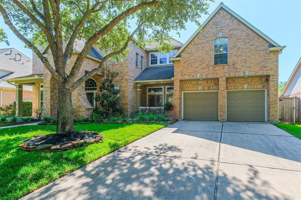 Charming front exterior with a lush, newly sodded yard, manicured flower beds, full sprinkler system, and a spacious three-car tandem garage.