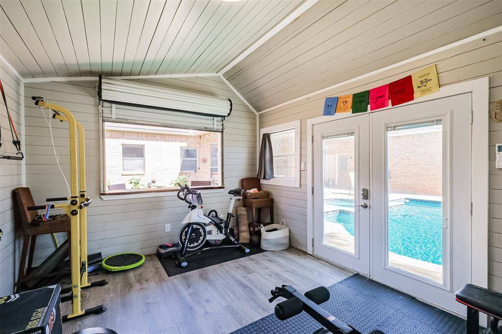 Discover the potential of this pool house, featuring a stylish roll-up serving bar, elegant painted wood interior, and inviting double doors.