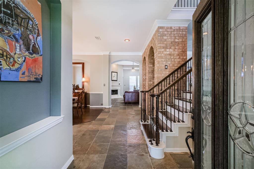 Welcome to your dream home, featuring elegant slate floors, stylish updated wood stairs with wrought iron balusters, and charming brick archways.
