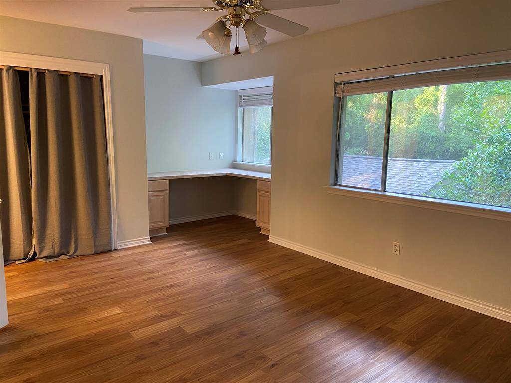The primary bedroom has lots of windows and a built-in desk!  The ceiling fan has been replaced; see other photos.