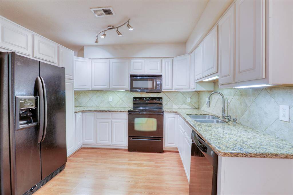 The kitchen features crisp white cabinets, granite countertops, and under cabinet lighting.