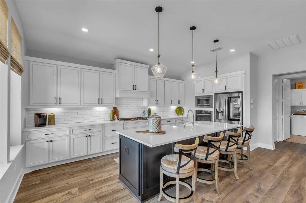 This dream kitchen features an oversized island with quartz countertops, upgraded cabinets and hardware.