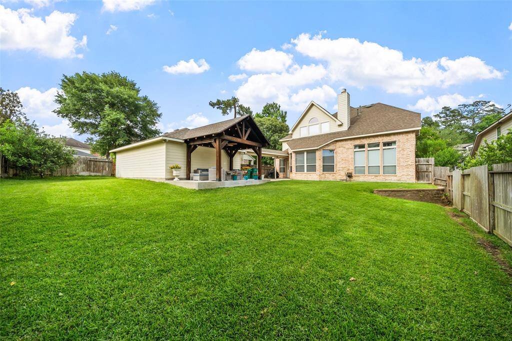 This charming two-story brick home features a well-maintained front yard with lush green grass and neatly trimmed hedges. It offers a welcoming walkway leading to the entrance, with a three-car garage visible to the side.