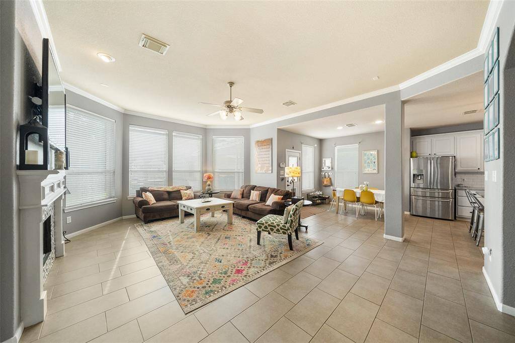 Bright and inviting living room with large windows, modern fireplace, built-in bookshelves, and a ceiling fan. It features a cozy seating area, stylish finishes, and ample natural light, creating an ideal space for relaxation and entertainment.