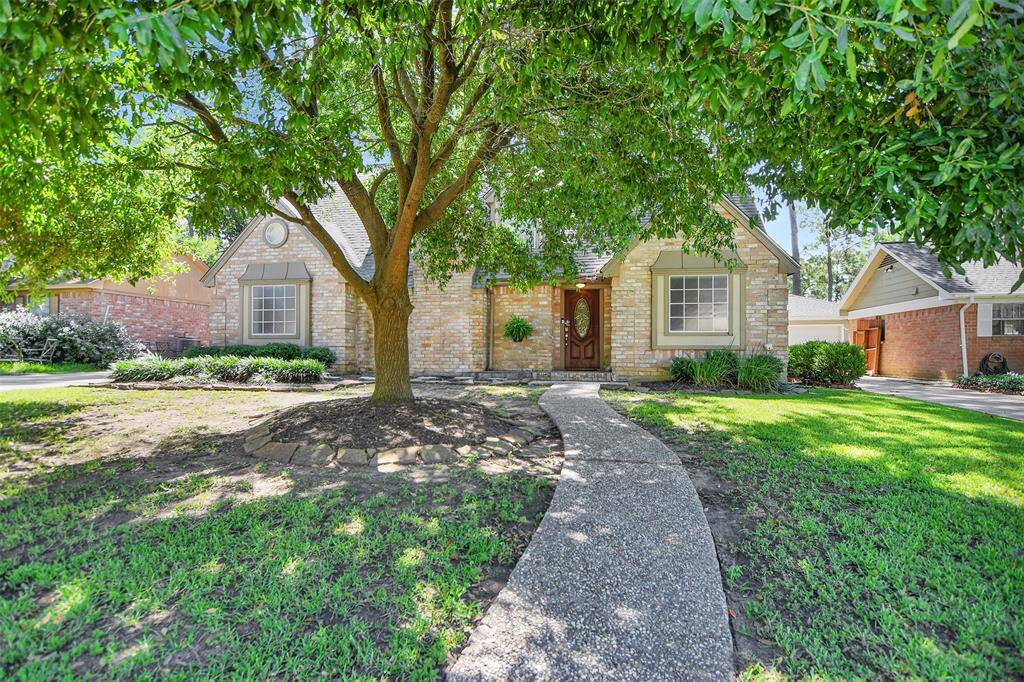 Charming brick home with a welcoming front path, nestled under a large, mature tree. The yard is well-maintained, offering a serene and private feel.